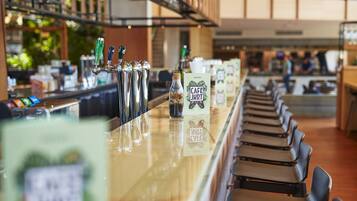 Een bar met verschillende bierkraan aansluitingen, een fles 'Cafe JKRT' drank en een menukaart standaard.