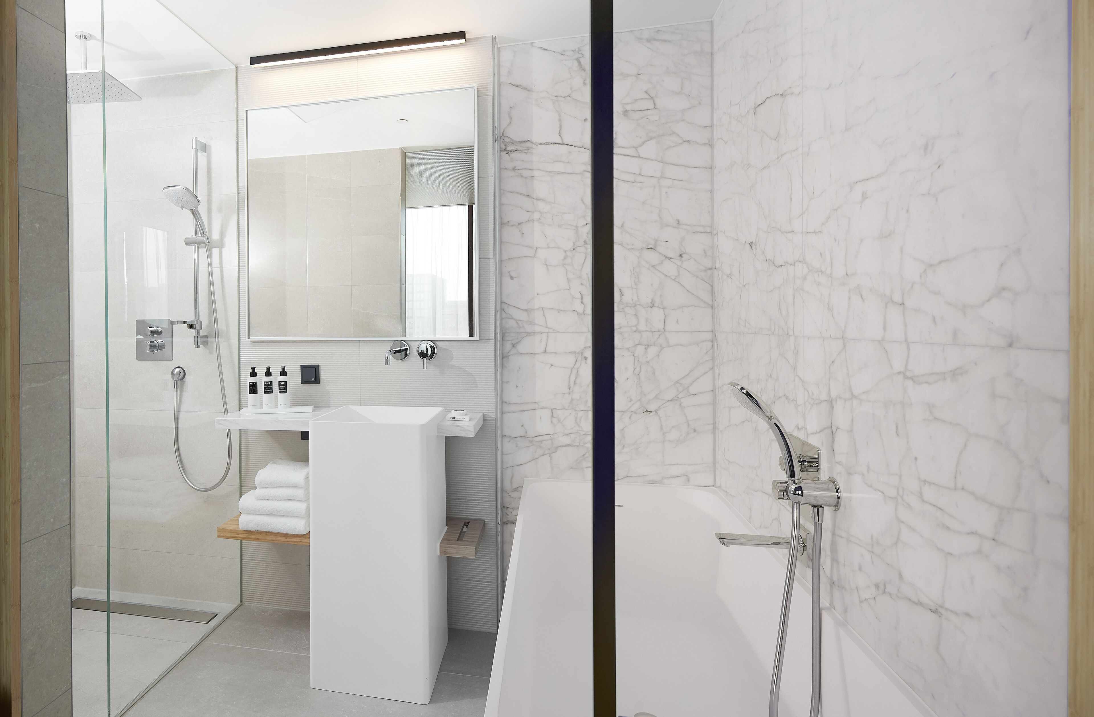 A modern bathroom with a glass-enclosed shower, a white sink, and a marble wall.