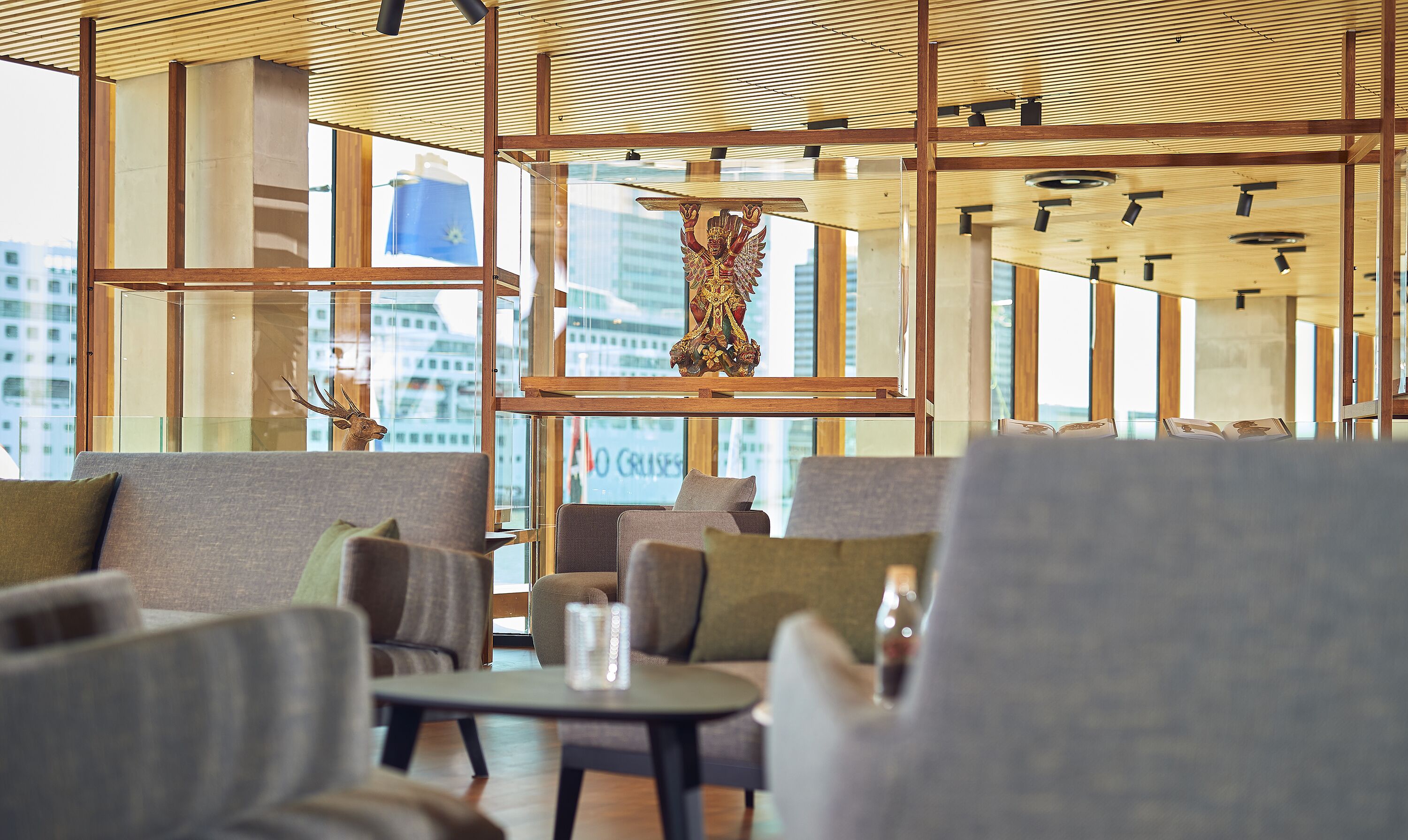 A modern interior with wooden beams, glass partitions, and seating areas.