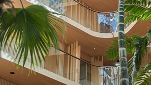 A multi-level atrium with glass railings and wooden paneling, featuring a central open space and multiple balconies.