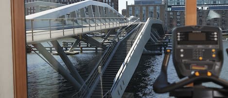 Un puente moderno con pasarela peatonal sobre el agua, rodeado de edificios urbanos.