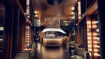 A modern bar area with a curved counter, seating, and ambient lighting.