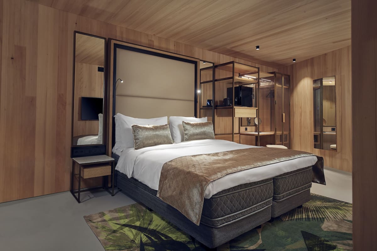 Une chambre à coucher moderne avec un grand lit, une table de chevet, un miroir et des étagères intégrées.