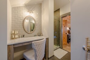 A bathroom with a white tiled backsplash, a round mirror with a gold frame, a vanity with a marble countertop, and a glass shower enclosure. - Luxury Mountain Cabin with Views (Banner Elk)