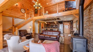 A spacious living area with a fireplace, leather sofas, and a staircase leading to an upper level. - Luxury Mountain Cabin with Views (Banner Elk)