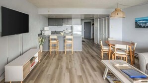 Un espacio habitable moderno con cocina, comedor y televisor montado en la pared.