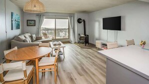 Una sala de estar moderna con un sofá, una mesa de comedor y sillas, un televisor y una chimenea.