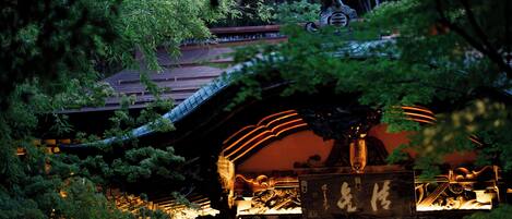 A traditional Japanese building with a tiled roof, surrounded by lush greenery.
