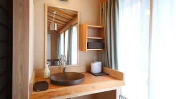 A wooden bathroom vanity with a round sink, a mirror, and a shelf unit.