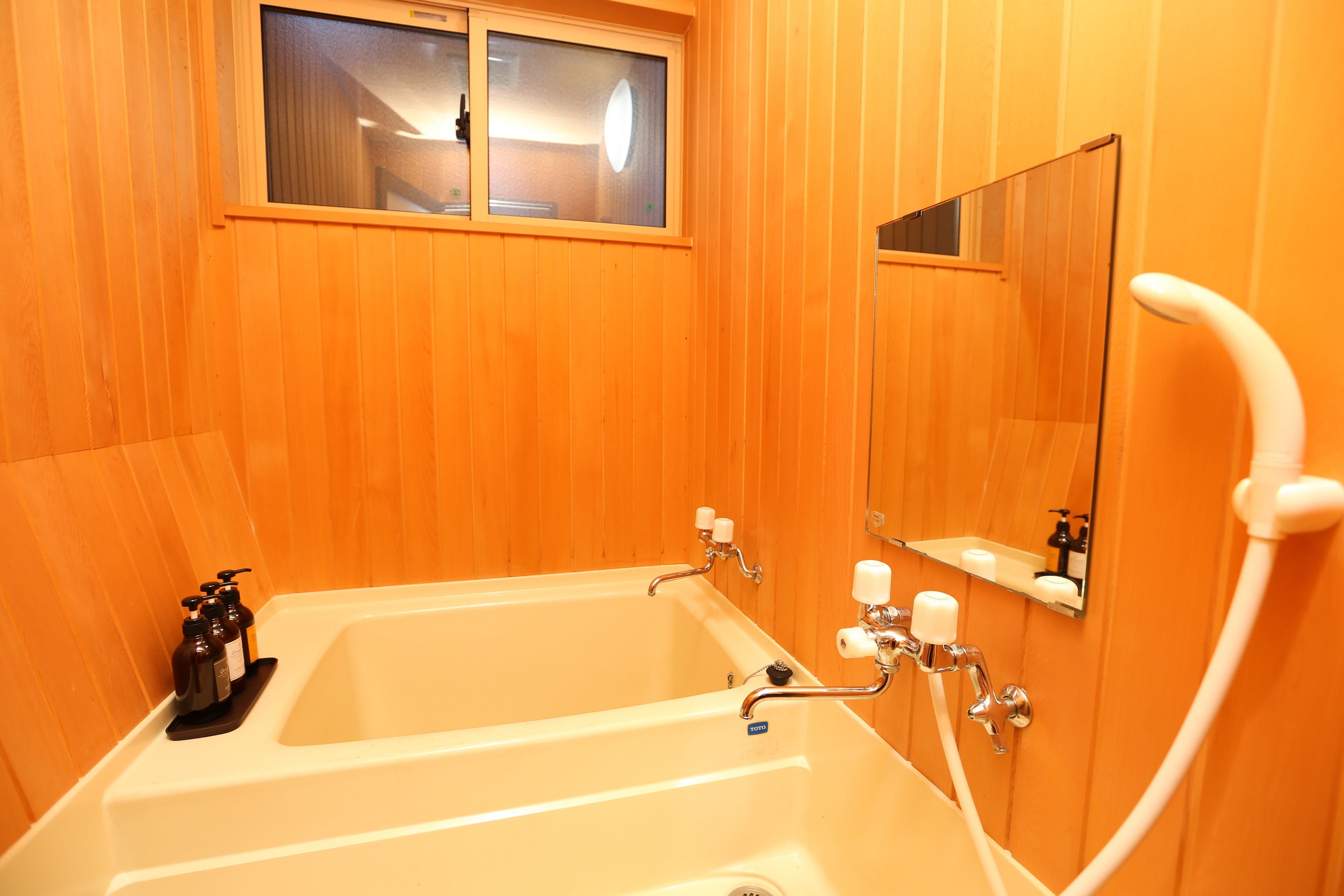A bathroom with wooden paneling, a bathtub, a shower, and a mirror.