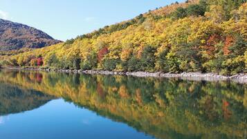 A calm lake reflecting colorful autumn trees and a mountain in the background.