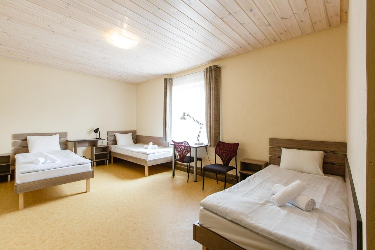 A hotel room with two beds, a desk, a chair, and a window with curtains.