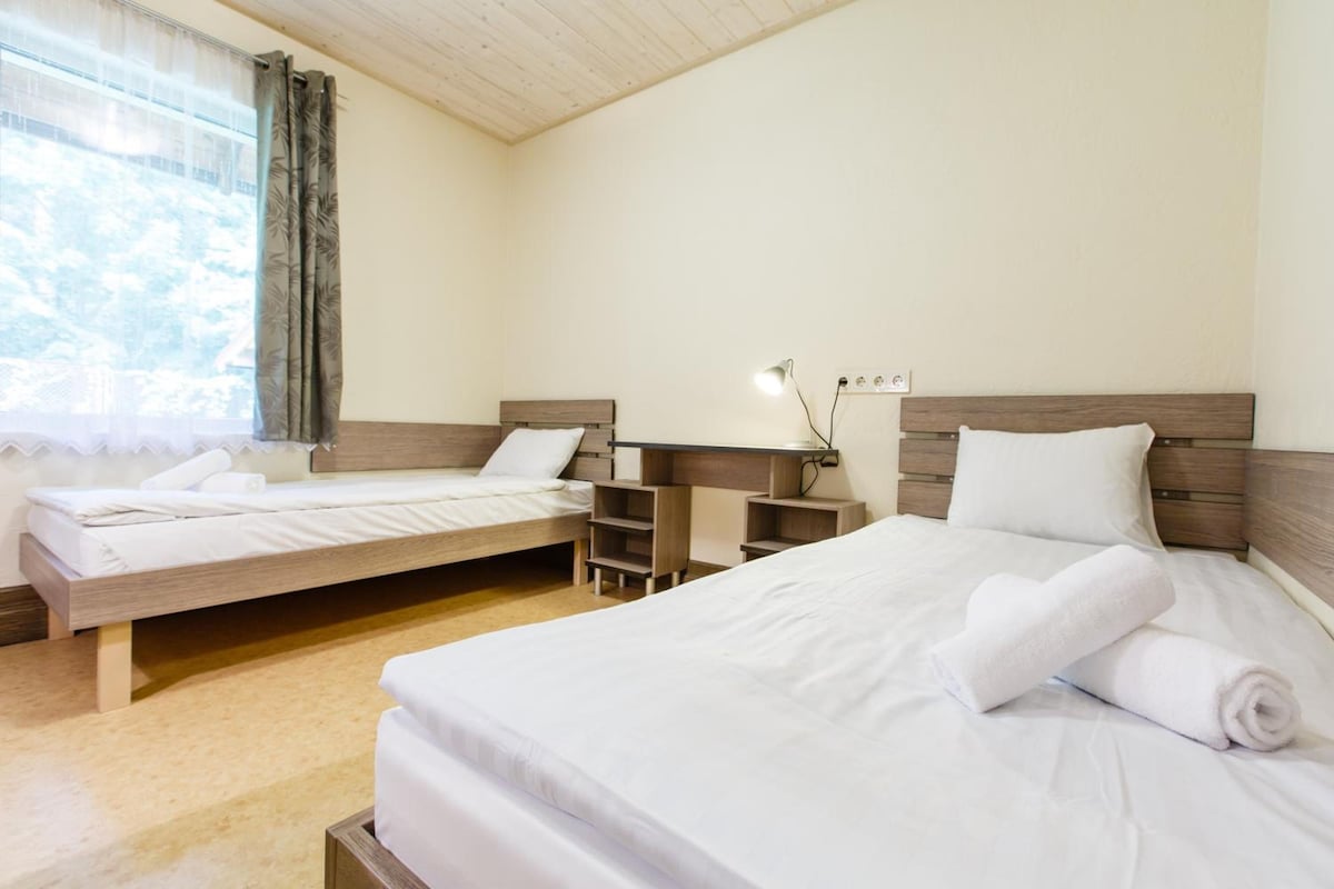A hotel room with two beds, a desk, and a lamp.