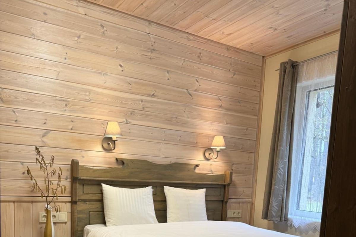 A wooden-paneled bedroom with a bed, nightstands, and wall-mounted lamps.