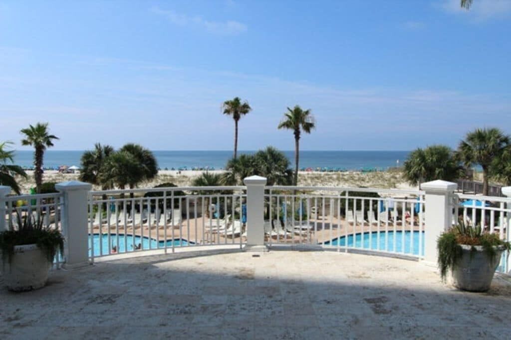 A gated pool area with a view of the beach and ocean.