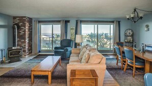 A living room with a sofa, coffee table, and dining area with chairs and a table. - Gearhart House G616 (Gearhart)