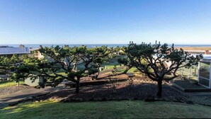 A view of a coastal landscape with a clear sky, a grassy area, and a few trees. - Gearhart House G616 (Gearhart)