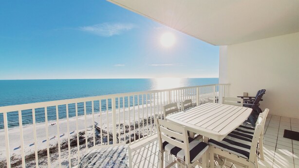 Un balcón con vistas al mar, una mesa y sillas.
