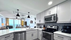 Una cocina moderna con electrodomésticos de acero inoxidable, armarios blancos y una isla grande con fregadero.