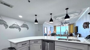 Una cocina moderna con una isla grande, electrodomésticos de acero inoxidable e iluminación colgante.
