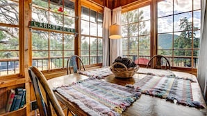 A wooden dining area with a table, chairs, and a basket of pinecones. - Larkspur Retreat- Breathtaking Views of Longs Peak! (Estes Park)