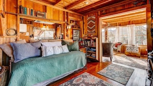 A cozy log cabin interior with a bed, bookshelves, and a fireplace. - Larkspur Retreat- Breathtaking Views of Longs Peak! (Estes Park)