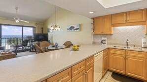 A kitchen with wooden cabinets, a dining area with a table and chairs, and a balcony with a view.
