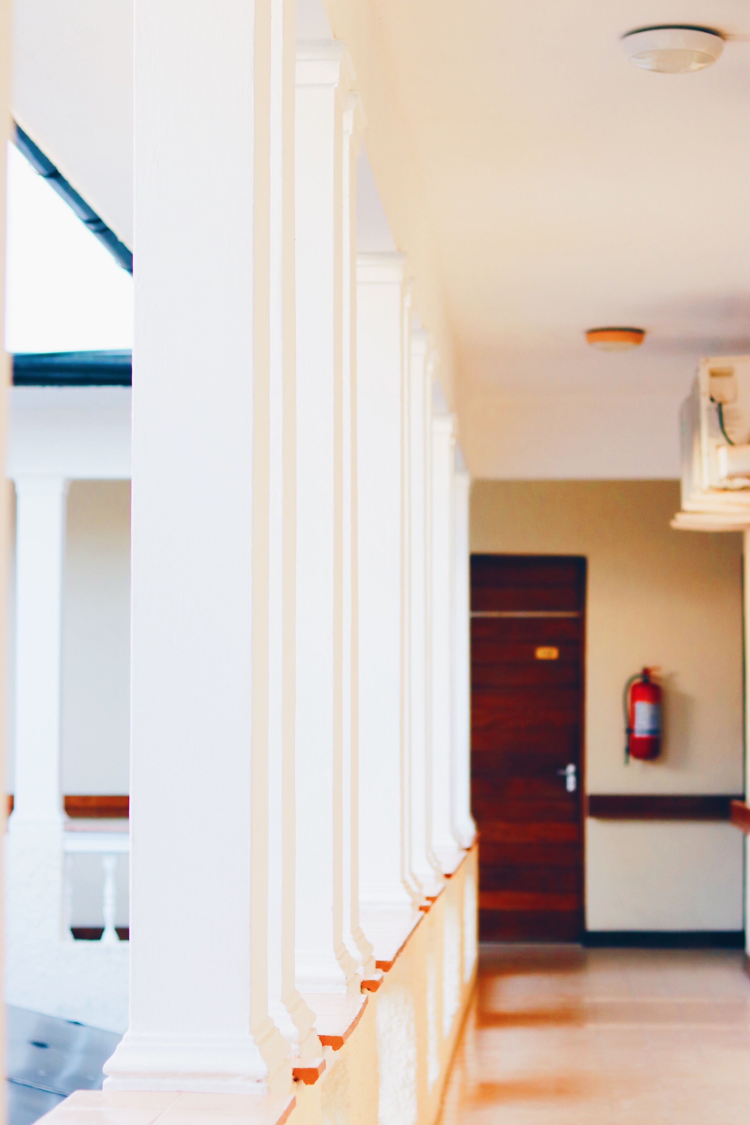 A corridor with white columns and a wooden floor.