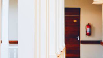 A corridor with white columns and a wooden floor.