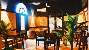 A cozy restaurant with wooden furniture, a large window, and a plant in the center. - Lotus Hotel (Mombasa)