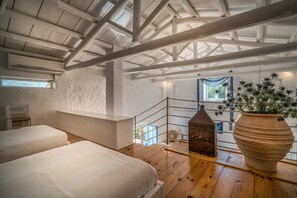 Een kamer met hoge plafonds, zichtbare balken, houten vloeren en een grote potplant.