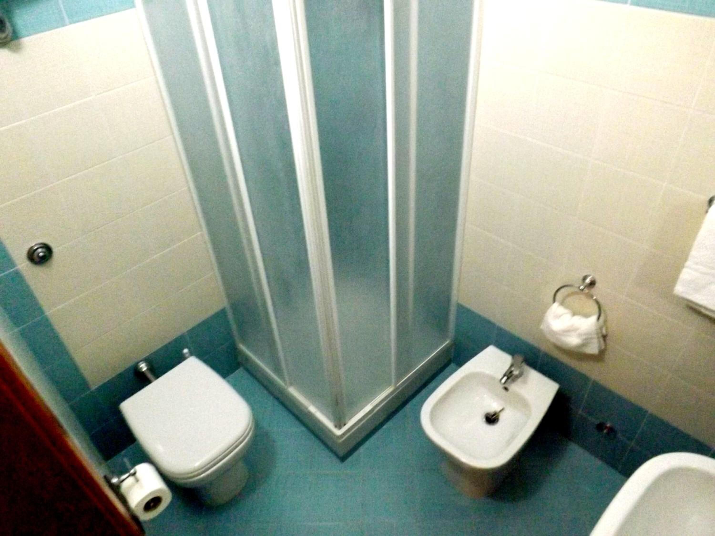 Un baño con ducha, inodoro, bidé y un perchero para toallas.
