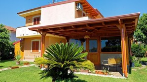Una casa de dos pisos con un porche cubierto, una antena parabólica y un jardín bien cuidado.