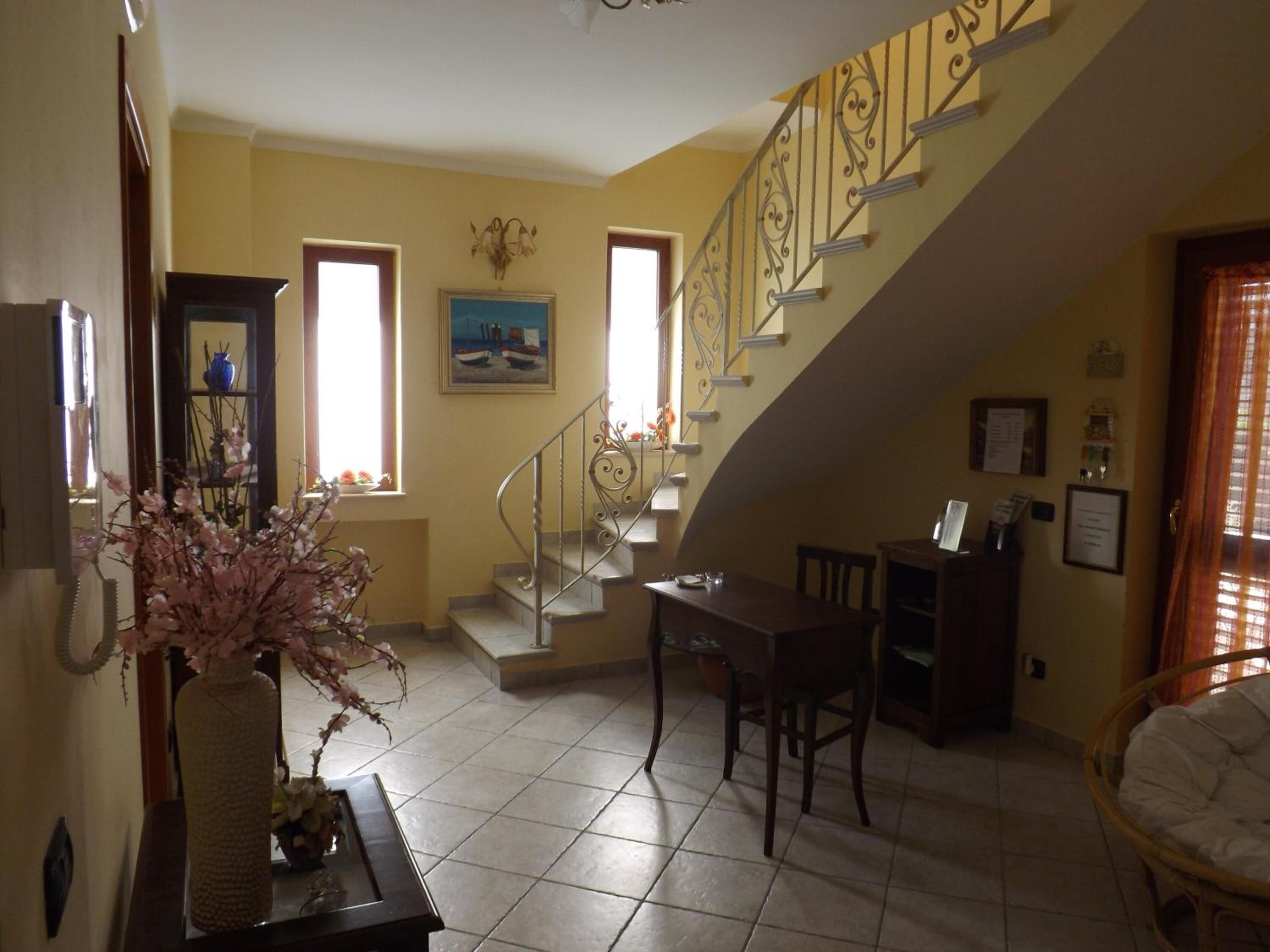 Uma sala de estar com escada, mesa de jantar e sofá.