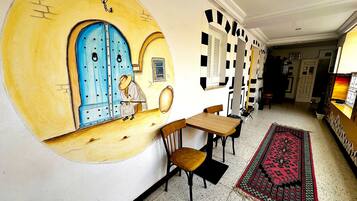 A hallway with a blue door, a patterned rug, and a small table with chairs.