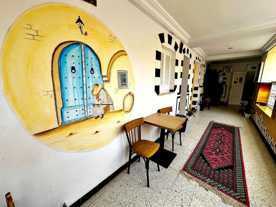 A hallway with a blue door, a patterned rug, and a small table with chairs.