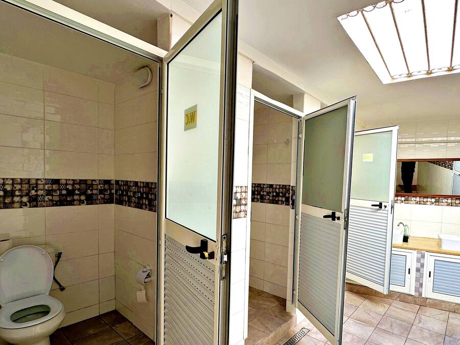A bathroom with a toilet, a shower area, and a sink.