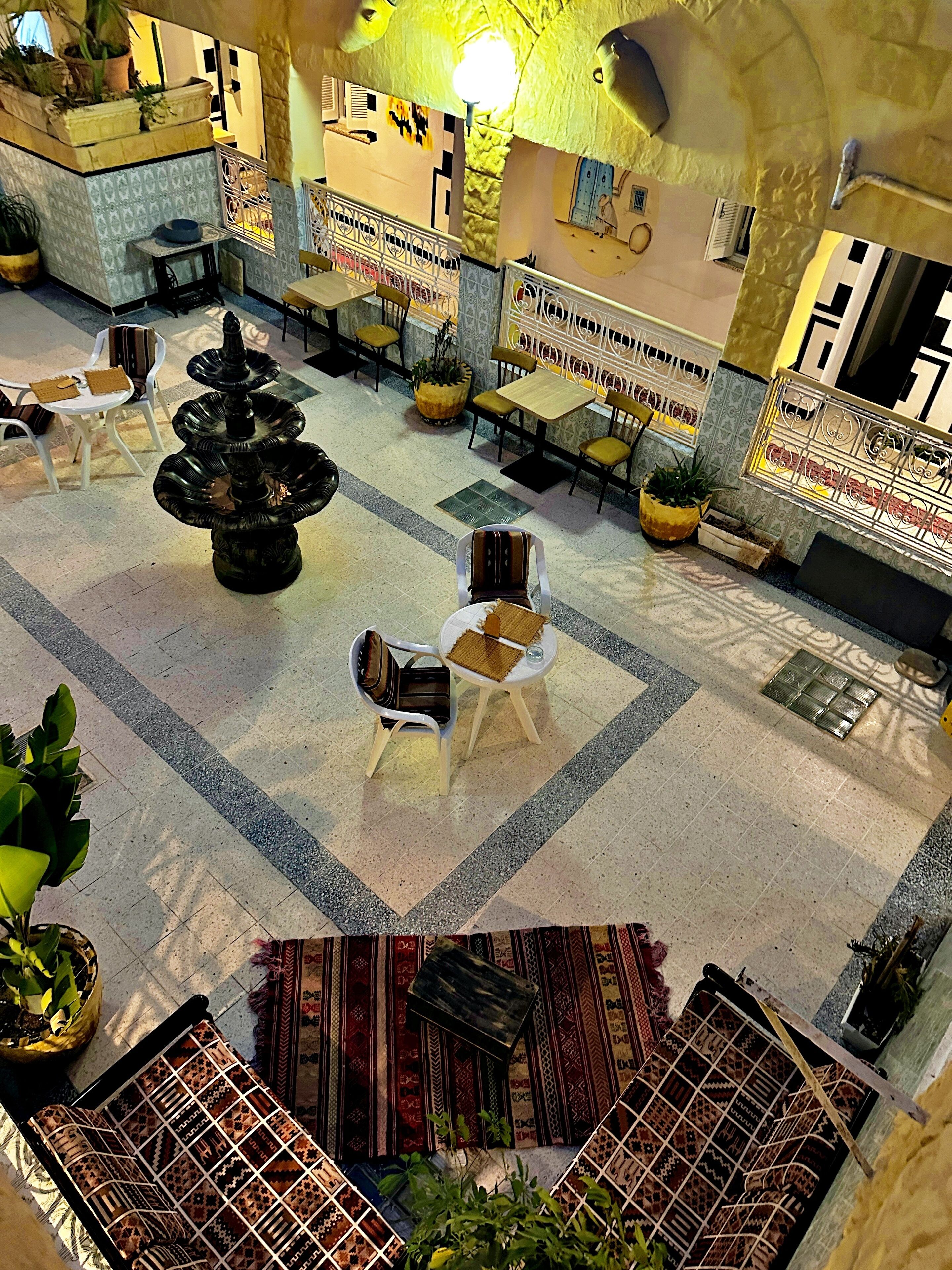 A spacious lobby with a central fountain, multiple seating areas, and potted plants.