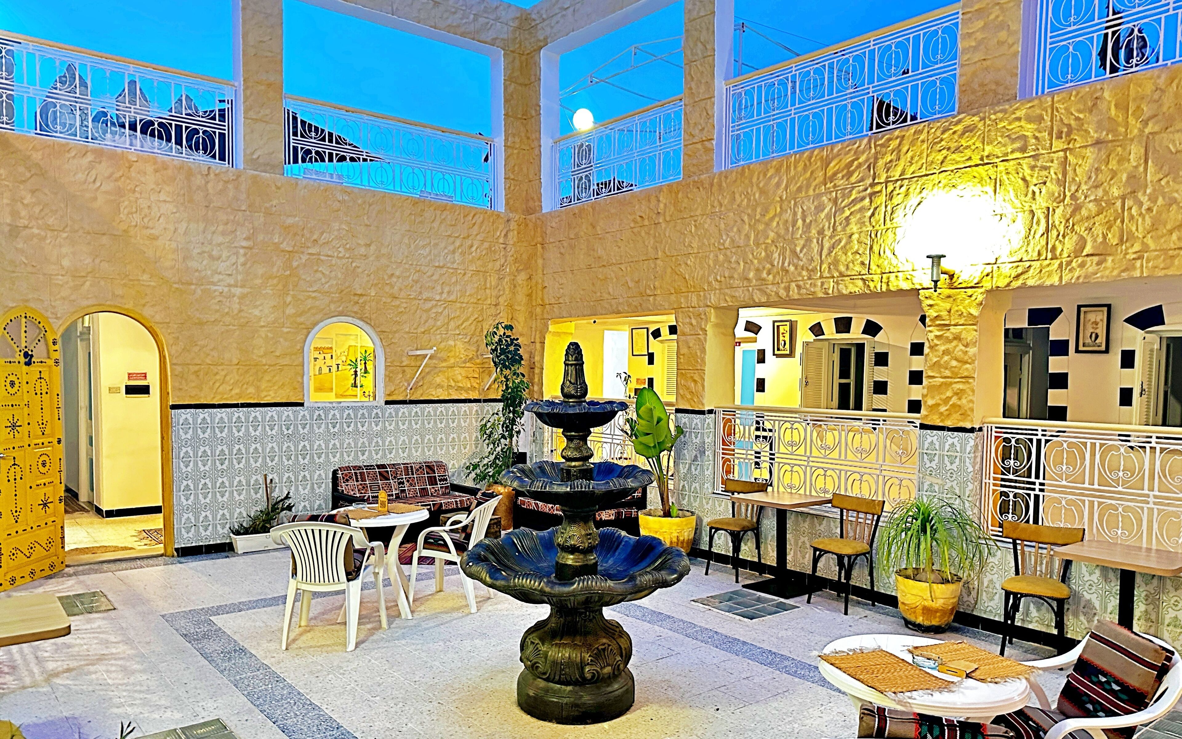 Een ruime lobby met een fontein in het midden, verschillende zithoeken en een hoge plafond met grote ramen.