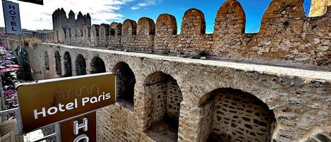 Un muro de piedra con pasajes en arco y un letrero que indica Hotel Paris.