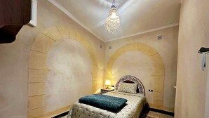 A room with a bed, a nightstand, a lamp, and a decorative ceiling light.
