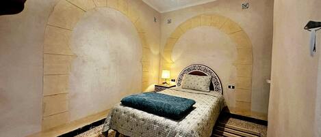 A room with a bed, a nightstand, a lamp, and a decorative ceiling light.