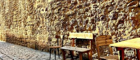 A cobblestone street with wooden benches and a stone wall.