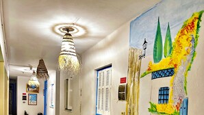 A hallway with a bench, a mural, and a ceiling fan.