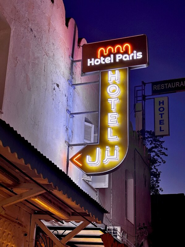 Un letrero de neón del 'Hotel Paris' con una flecha que indica izquierda.
