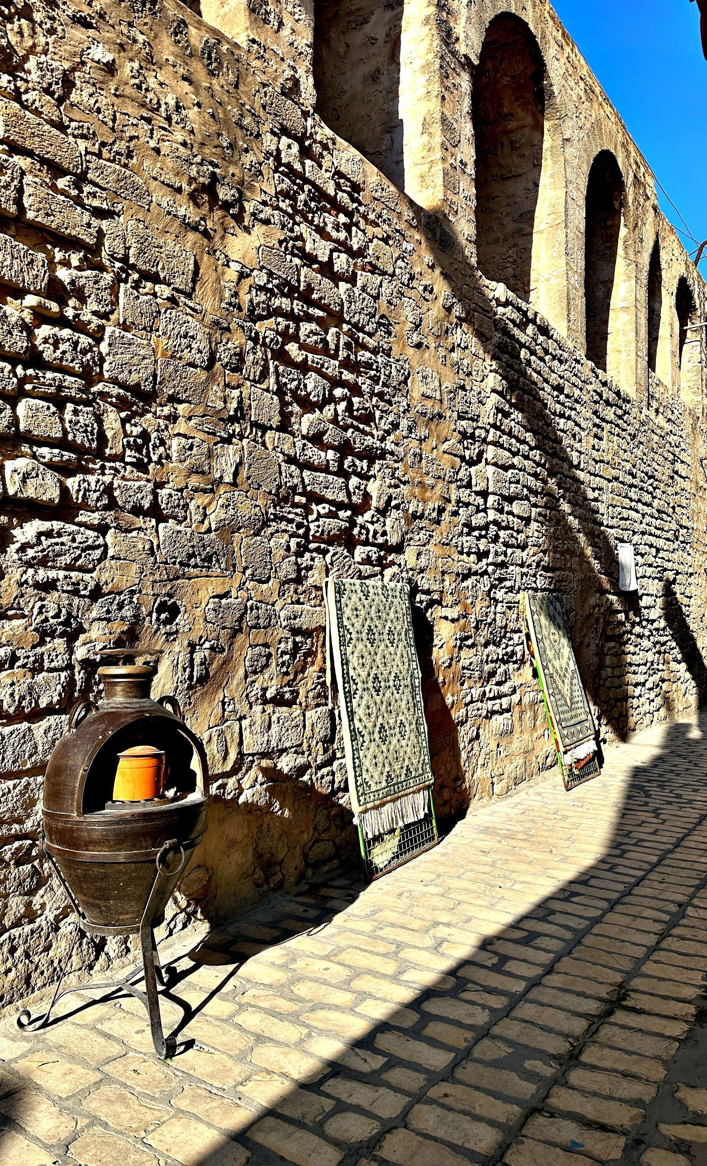 A stone wall with a traditional clay pot and a hanging cloth.