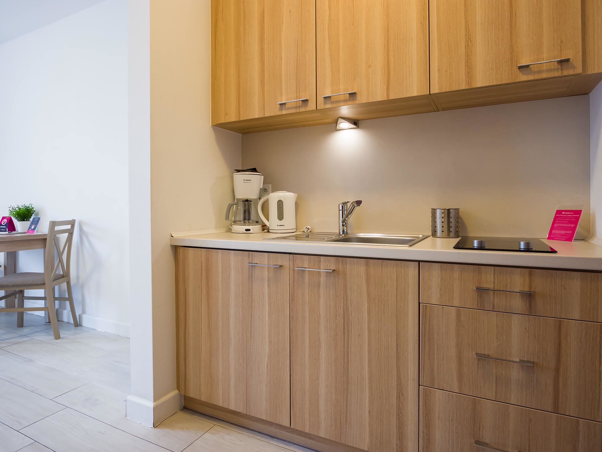 A modern kitchen with wooden cabinets, a built-in sink, and a coffee maker.