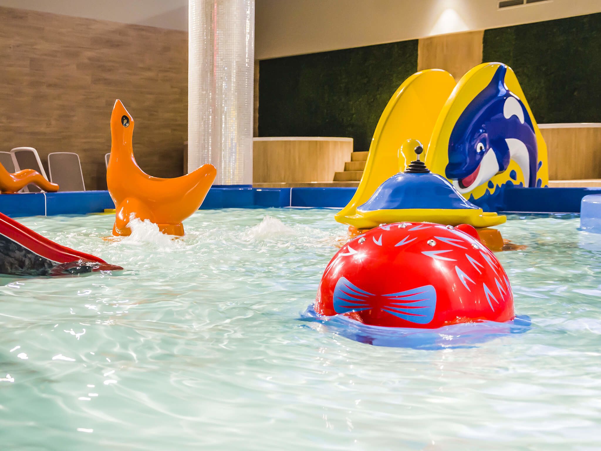 Ein Poolbereich mit verschiedenen bunten Wasserspielen und einer Rutsche.