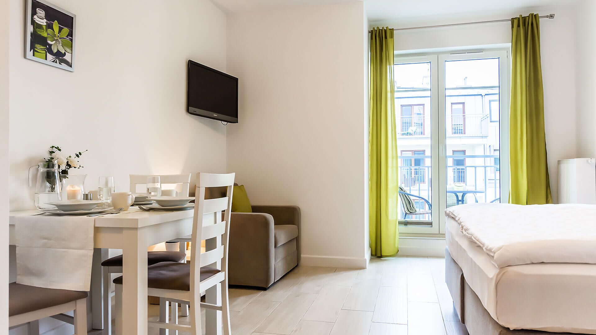Una habitación de hotel con cama, escritorio con silla, televisión y ventana con cortinas.