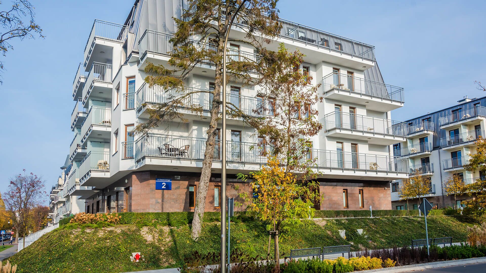 A multi-story residential building with balconies, a visible entrance, and a number '2' sign.